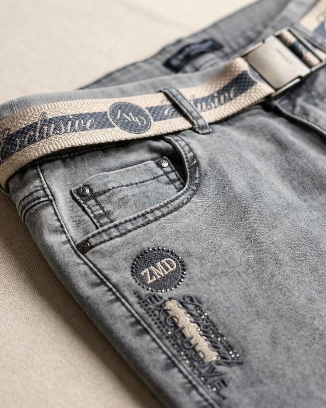 Κοντινή λεπτομέρεια σε γκρι καθημερινό τζιν παντελόνι μεγάλα μεγέθη, που δείχνει την υφασμάτινη ζώνη, την τσέπη και το έμβλημα ZMD με στρασάκια.