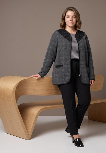 Γυναίκα φορά γκρι ανάγλυφη ζακέτα με μαύρες λεπτομέρειες με πουά, μπροστά σε ξύλινο πάγκο.