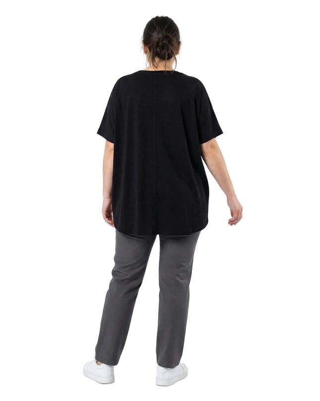 Πίσω όψη σε λευκό φόντο: Γυναικεία μαύρη τουνίκ plus size με κοντά μανίκια και κάθετη ραφή στην πλάτη. Διακρίνεται η εβαζέ γραμμή και το μακρύτερο τελείωμα.