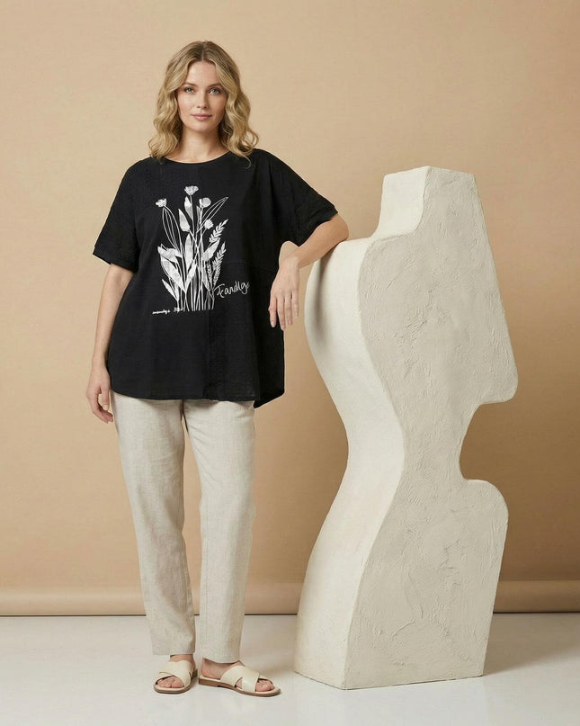 Ολόσωμη λήψη της γυναικείας μαύρης καλοκαιρινής τουνίκ plus size με φλοράλ απλικέ, φορεμένη από μοντέλο.