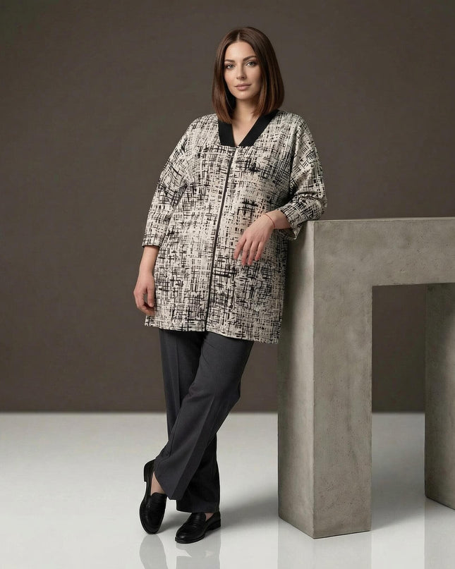 Γυναικεία plus size ζακέτα σε μπεζ χρώμα με μαύρο αφηρημένο σχέδιο και V γιακά. Ολόσωμη λήψη σε στούντιο, συνδυασμένη με μαύρο παντελόνι.