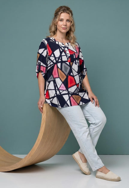Ολόσωμη λήψη με μοντέλο: Γυναικεία τουνίκ plus size με πολύχρωμο γεωμετρικό μοτίβο, άνετη γραμμή Α και V λαιμόκοψη. Συνδυασμένη με ανοιχτόχρωμο τζιν.