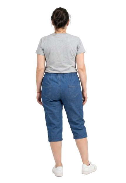 Γυναικείο μπλε ελαστικό τζιν παντελόνι 7/8 plus size, σε πίσω όψη όπου διακρίνονται οι εξωτερικές τσέπες και η άνετη εφαρμογή. Φωτογράφιση σε λευκό φόντο.