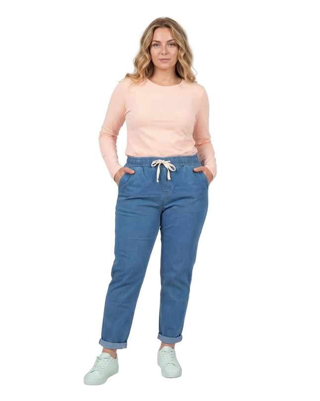 Ολόσωμη λήψη σε λευκό φόντο: Γυναικείο μπλε καλοκαιρινό τζιν σε μεγάλα μεγέθη με ίσια γραμμή, λευκό κορδόνι στη μέση και γυρισμένα ρεβέρ.