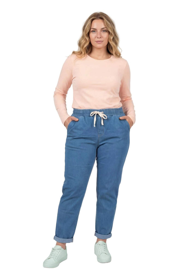 Ολόσωμη λήψη σε λευκό φόντο: Γυναικείο μπλε καλοκαιρινό τζιν σε μεγάλα μεγέθη με ίσια γραμμή, λευκό κορδόνι στη μέση και γυρισμένα ρεβέρ.