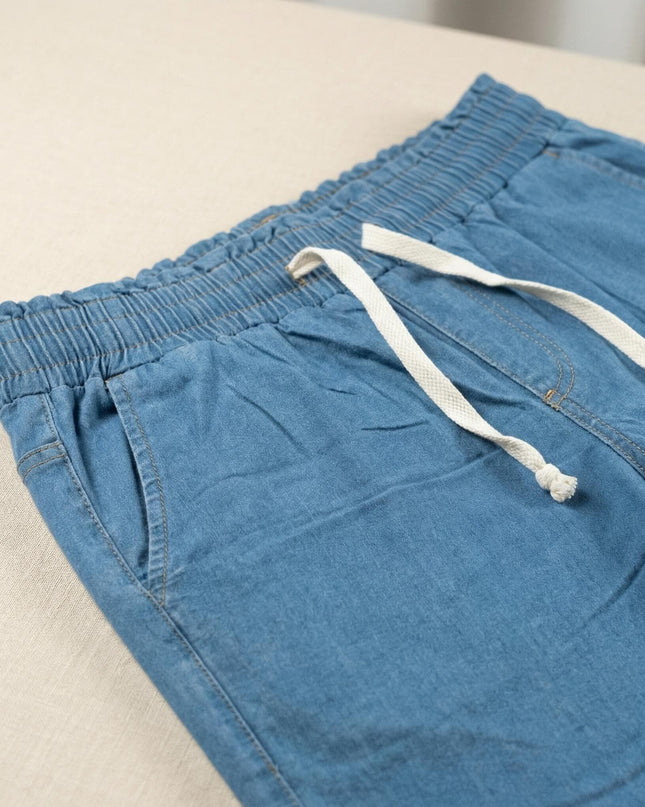 Κοντινή λεπτομέρεια στο γυναικείο μπλε καλοκαιρινό τζιν σε μεγάλα μεγέθη, που αναδεικνύει την ελαστική μέση με το λευκό κορδόνι και την πλαϊνή τσέπη.