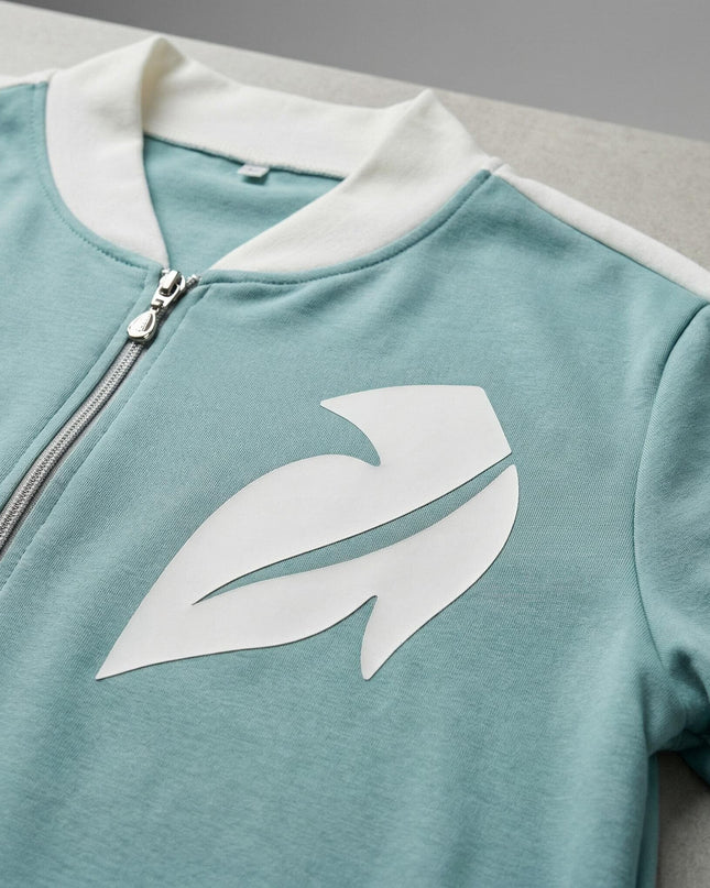 Κοντινή λεπτομέρεια από γυναικείο plus size σετ σε ανοιχτό πράσινο, με λευκό σχέδιο από οικολογικό δέρμα στο στήθος και φερμουάρ.