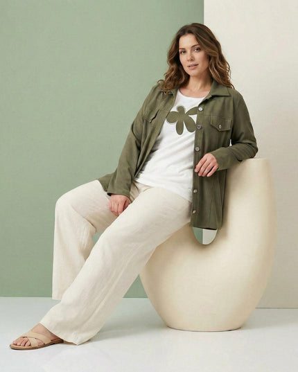 Γυναικείο σετ δύο τεμαχίων plus size που αποτελείται από χακί σακάκι και λευκό t-shirt με μεγάλη στάμπα, σε καθιστή ολόσωμη λήψη.