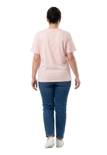 Ολόσωμη λήψη από πίσω: γυναικείο βαμβακερό t-shirt μεγάλα μεγέθη σε απαλό ροζ χρώμα, συνδυασμένο με τζιν παντελόνι και λευκά αθλητικά παπούτσια.