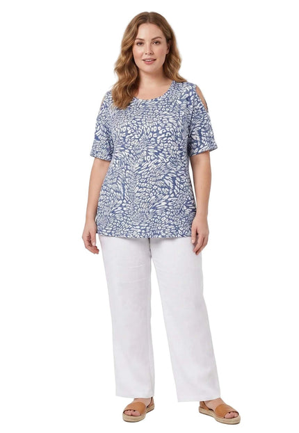 Ολόσωμη λήψη σε λευκό φόντο με plus size καλοκαιρινή τουνίκ με έξω ώμους, σε μπλε και λευκό μοτίβο, συνδυασμένη με λευκό παντελόνι.
