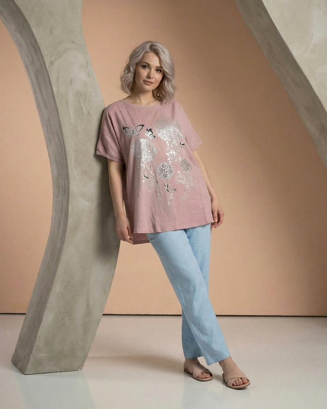 Ολόσωμη λήψη γυναίκας που φοράει απαλό ροζ καλοκαιρινή βαμβακερή τουνίκ μεγάλα μεγέθη, με εντυπωσιακό ασημένιο τύπωμα πεταλούδας.