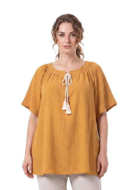 Γυναικεία τουνίκ plus size σε κίτρινο της μουστάρδας, με λευκά κορδόνια και φούντες στη λαιμόκοψη. Μπροστινή όψη σε λευκό φόντο.