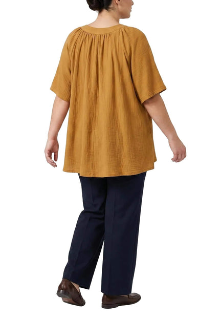 Πίσω όψη από γυναικεία τουνίκ plus size σε κίτρινο της μουστάρδας. Φαίνεται η άνετη γραμμή και οι λεπτομέρειες με σούρες στην πλάτη, σε λευκό φόντο.