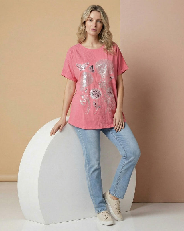 Ολόσωμη λήψη της κοραλί εβαζέ τουνίκ με φλοράλ σχέδιο, μεγάλα μεγέθη, φορεμένη από μοντέλο. Φαίνεται το μπροστινό μέρος και τα κοντά μανίκια.