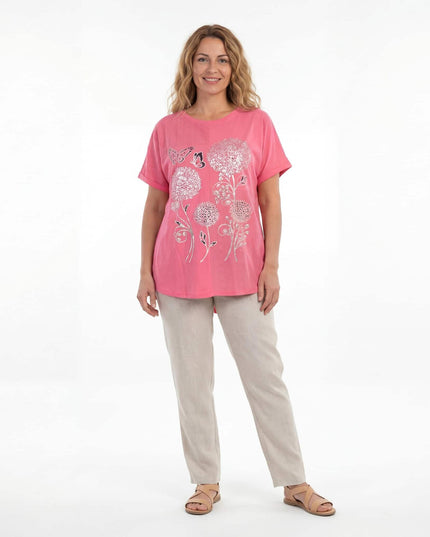 Ολόσωμη λήψη σε λευκό φόντο. Μοντέλο φοράει καθημερινή κοραλί μάξι τουνίκ σε μεγάλα μεγέθη, με εντυπωσιακό ασημένιο φλοράλ τύπωμα και μπεζ παντελόνι.