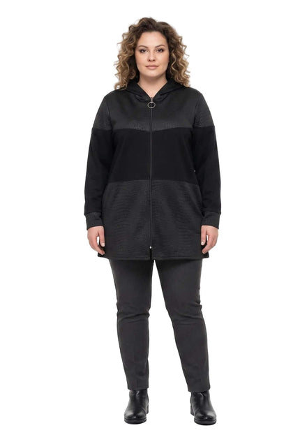 Ολόσωμη λήψη σε λευκό φόντο με καθημερινή μαύρη ζακέτα σε μεγάλα μεγέθη, που διαθέτει φερμουάρ, κουκούλα και ανάγλυφες λεπτομέρειες.