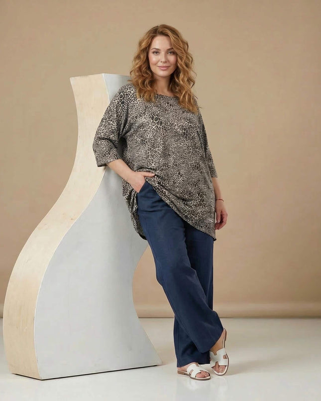 Ολόσωμη λήψη γυναίκας που φοράει την καθημερινή μάξι λεοπάρ τουνίκ σε μεγάλα μεγέθη, με 3/4 μανίκια, μπροστά από ανοιχτό καφέ φόντο.
