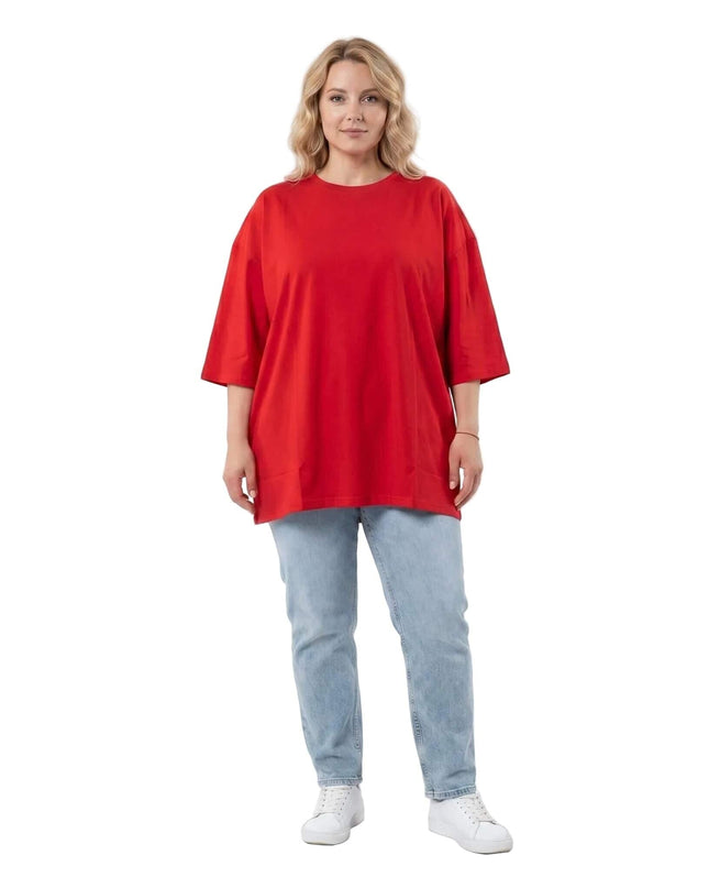 Ολόσωμη λήψη: Κόκκινο βαμβακερό t-shirt σε μεγάλα μεγέθη, με στρογγυλή λαιμόκοψη και φαρδιά ίσια γραμμή, συνδυασμένο με ανοιχτόχρωμο τζιν παντελόνι.