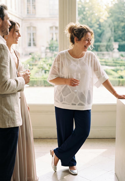 Ολόσωμη λήψη με κομψή γυναικεία τουνίκ σε λευκό χρώμα με γεωμετρικό σχέδιο, ιδανική για μεγάλα μεγέθη, συνδυασμένη με κομψό μπλε παντελόνι.