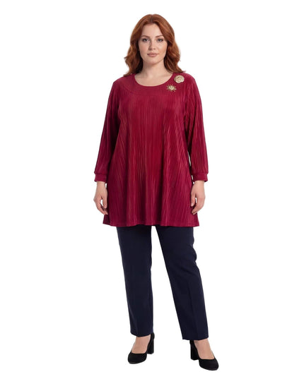 Ολόσωμη λήψη γυναίκας με κομψή επίσημη κόκκινη τουνίκ σε μεγάλα μεγέθη. Ξεχωρίζει το ριχτό πλισέ ύφασμα και οι χρυσές καρφίτσες στο ντεκολτέ.