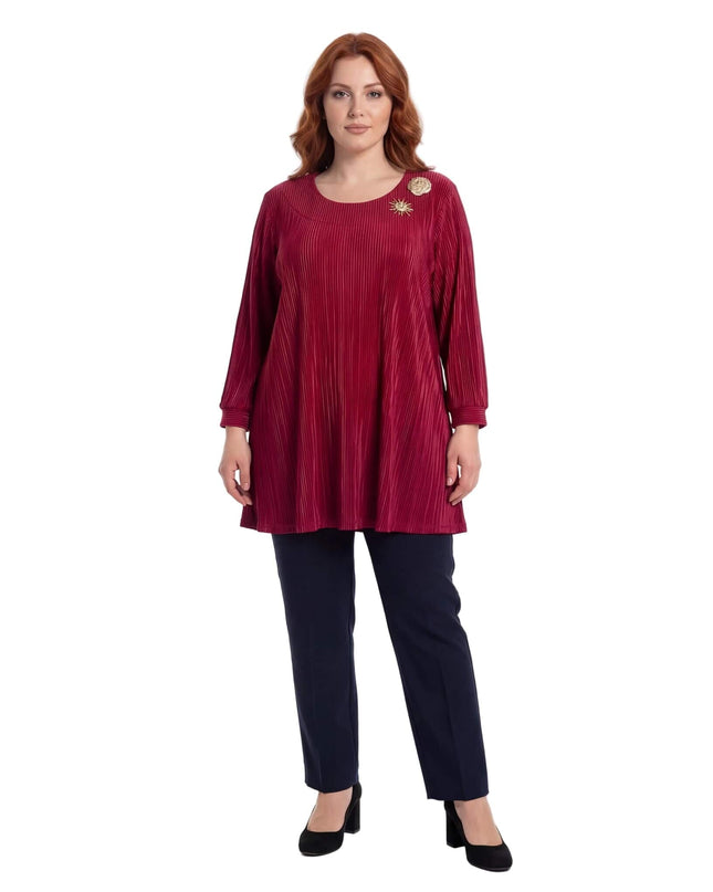 Ολόσωμη λήψη γυναίκας με κομψή επίσημη κόκκινη τουνίκ σε μεγάλα μεγέθη. Ξεχωρίζει το ριχτό πλισέ ύφασμα και οι χρυσές καρφίτσες στο ντεκολτέ.