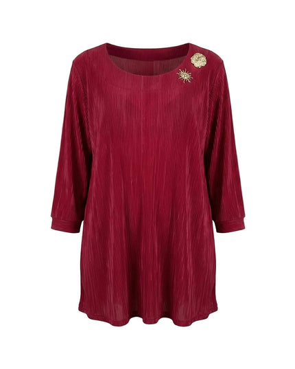 Κομψή επίσημη κόκκινη τουνίκ σε μεγάλα μεγέθη με πλισέ ύφασμα, μανίκια 7/8 και δύο χρυσές καρφίτσες στο ντεκολτέ, φωτογραφημένη σε λευκό φόντο.