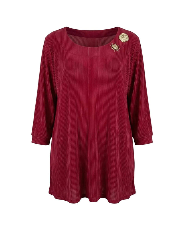 Κομψή επίσημη κόκκινη τουνίκ σε μεγάλα μεγέθη με πλισέ ύφασμα, μανίκια 7/8 και δύο χρυσές καρφίτσες στο ντεκολτέ, φωτογραφημένη σε λευκό φόντο.
