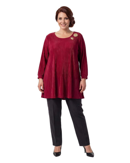 Ολόσωμη λήψη: Κομψή επίσημη κόκκινη τουνίκ σε μεγάλα μεγέθη, με πλισέ υφή, μανίκια 7/8 και εντυπωσιακές χρυσές καρφίτσες, σε λευκό φόντο.