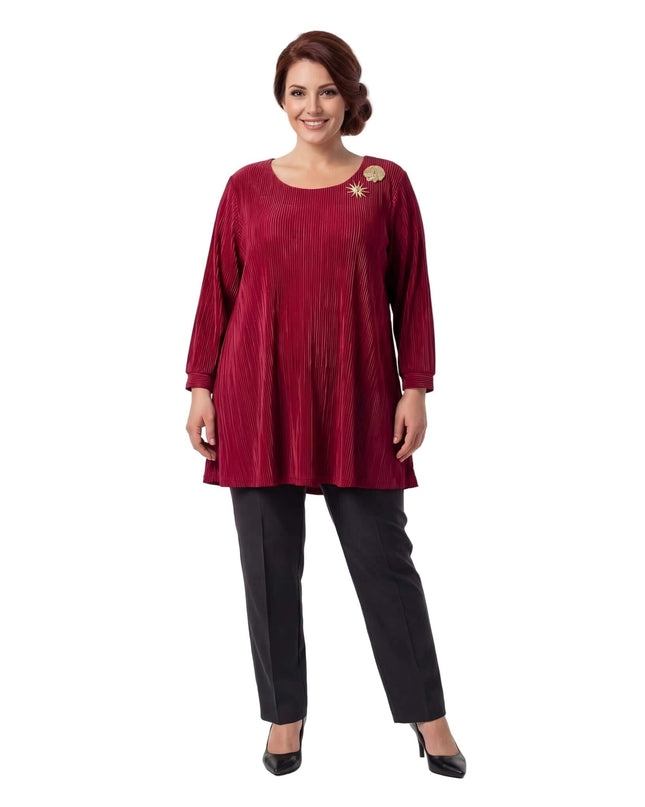 Ολόσωμη λήψη: Κομψή επίσημη κόκκινη τουνίκ σε μεγάλα μεγέθη, με πλισέ υφή, μανίκια 7/8 και εντυπωσιακές χρυσές καρφίτσες, σε λευκό φόντο.