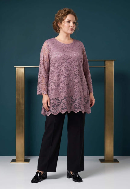 Ολόσωμη λήψη με κομψή δαντελένια τουνίκ σε χρώμα σάπιο μήλο και μεγάλα μεγέθη, συνδυασμένη με μαύρο παντελόνι.