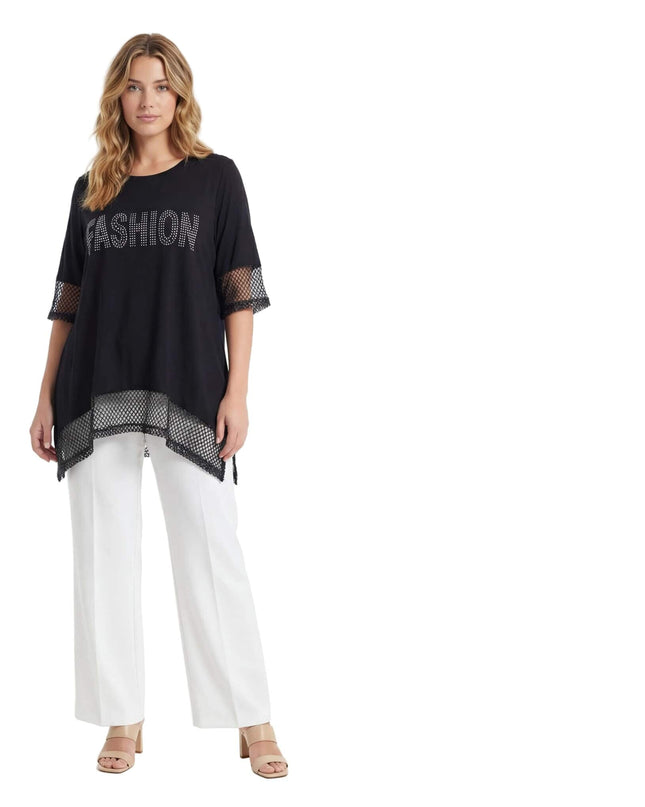 Ολόσωμη λήψη σε λευκό φόντο. Μαύρη ασύμμετρη τουνίκ plus size με λεπτομέρειες από δίχτυ στα μανίκια και το τελείωμα, και επιγραφή FASHION με στρας.