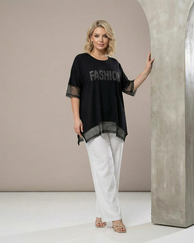 Ολόσωμη λήψη μοντέλου με μαύρη ασύμμετρη τουνίκ plus size. Ξεχωρίζουν οι λεπτομέρειες από δίχτυ και η επιγραφή με στρας στο μπροστινό μέρος.