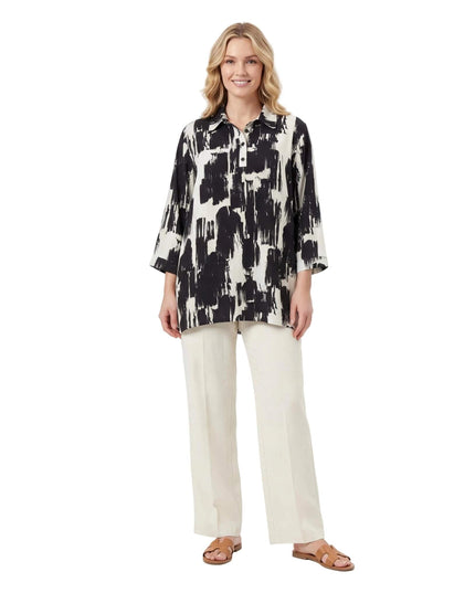 Ολόσωμη λήψη σε λευκό φόντο. Μοντέλο φοράει κομψό ασπρόμαυρο πουκάμισο σε μεγάλα μεγέθη με αφηρημένο σχέδιο, γιακά και μανίκια 3/4.