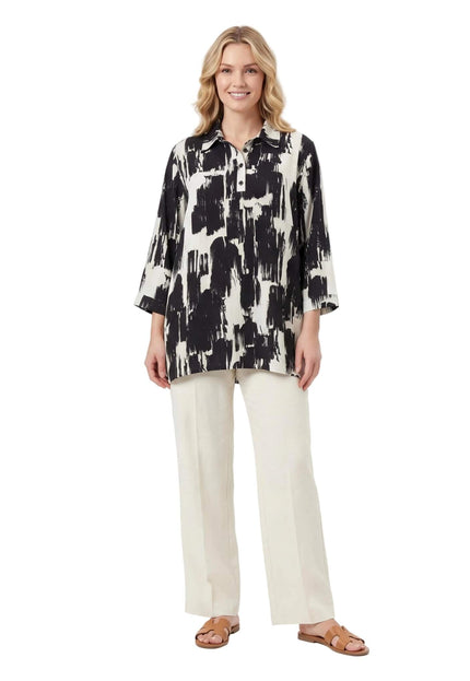 Ολόσωμη λήψη σε λευκό φόντο. Μοντέλο φοράει κομψό ασπρόμαυρο πουκάμισο σε μεγάλα μεγέθη με αφηρημένο σχέδιο, γιακά και μανίκια 3/4.