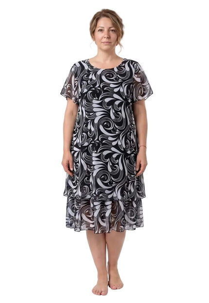 Κομψό ασπρόμαυρο μίντι φόρεμα plus size με αφηρημένο σχέδιο και διπλό βολάν από σιφόν. Ολόσωμη μπροστινή λήψη του μοντέλου σε λευκό φόντο.