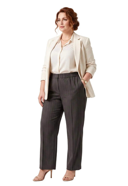 Κομψό γυναικείο παντελόνι σε μεγάλα μεγέθη, σε σκούρο γκρι χρώμα με λεπτή ρίγα, φορεμένο με μπεζ σακάκι, σε ολόσωμη λήψη σε λευκό φόντο.