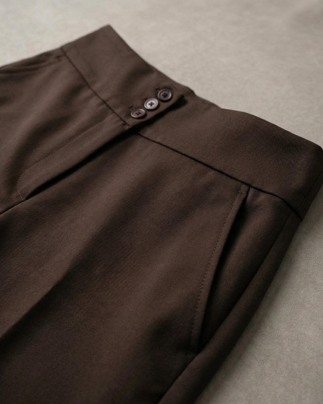 Κοντινή λεπτομέρεια της μέσης σε κομψό καφέ παντελόνι μεγάλα μεγέθη, που αναδεικνύει τα διακοσμητικά κουμπιά, την πλαϊνή τσέπη και την ποιότητα του υφάσματος.