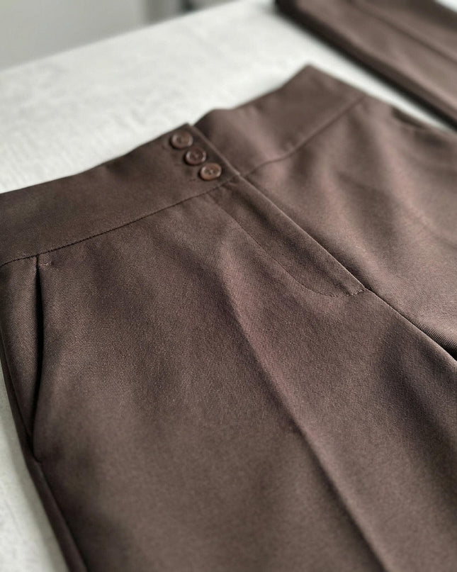 Κοντινή λεπτομέρεια από καφέ ψηλόμεσο παντελόνι σε μεγάλα μεγέθη, που εστιάζει στα τρία κουμπιά της ζώνης και την ποιοτική ραφή.