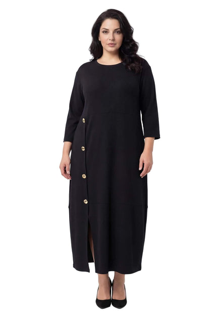 Ολόσωμη λήψη σε λευκό φόντο. Κομψό μαύρο επίσημο εβαζέ φόρεμα σε μεγάλα μεγέθη με 7/8 μανίκια, διακοσμητικά χρυσά κουμπιά και σκίσιμο.