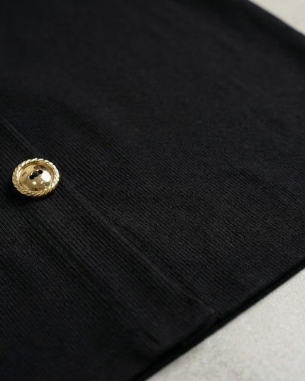 Κοντινή λεπτομέρεια από το μαύρο ριμπ ύφασμα του επίσημου φορέματος σε μεγάλα μεγέθη, με εστίαση στο εντυπωσιακό χρυσό διακοσμητικό κουμπί.