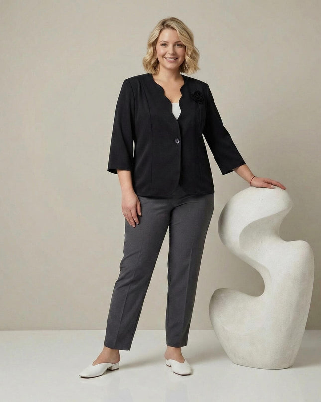 Ολόσωμη λήψη όπου μοντέλο φοράει το κομψό μαύρο σακάκι σε μεγάλα μεγέθη με το εντυπωσιακό 3D τριαντάφυλλο, συνδυασμένο με γκρι παντελόνι.