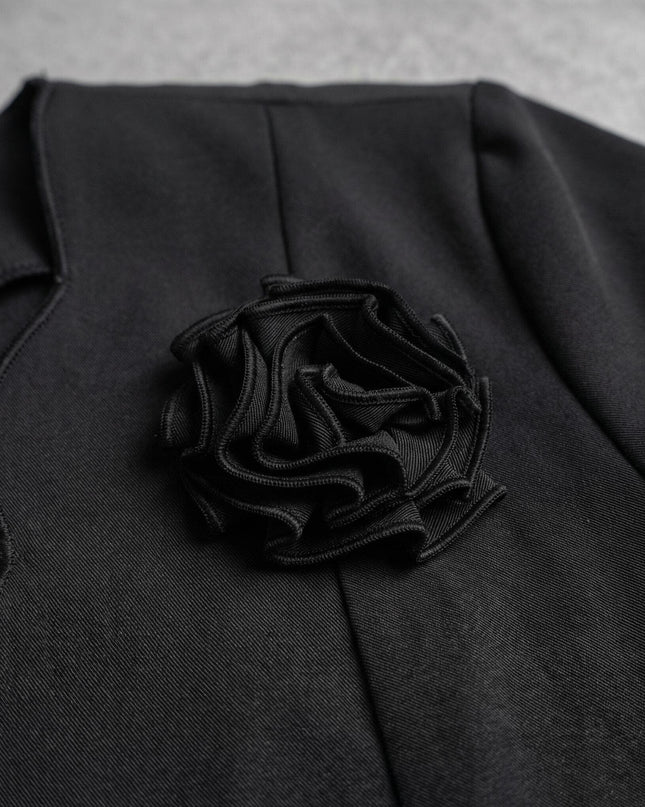 Κοντινή λεπτομέρεια στο εντυπωσιακό 3D υφασμάτινο τριαντάφυλλο που διακοσμεί το κομψό μαύρο γυναικείο σακάκι plus size.