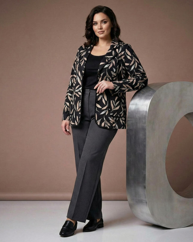 Ολόσωμη λήψη μοντέλου που φοράει κομψό μαύρο σακάκι μεγάλα μεγέθη με αφηρημένο σχέδιο φύλλων σε μπεζ τόνους, συνδυασμένο με γκρι παντελόνι.