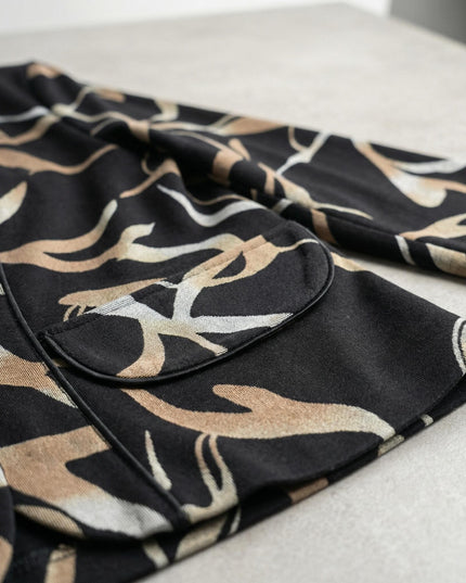 Λεπτομέρεια τσέπης και υφής από κομψό μαύρο σακάκι μεγάλα μεγέθη με αφηρημένο μπεζ σχέδιο σε κοντινή λήψη.