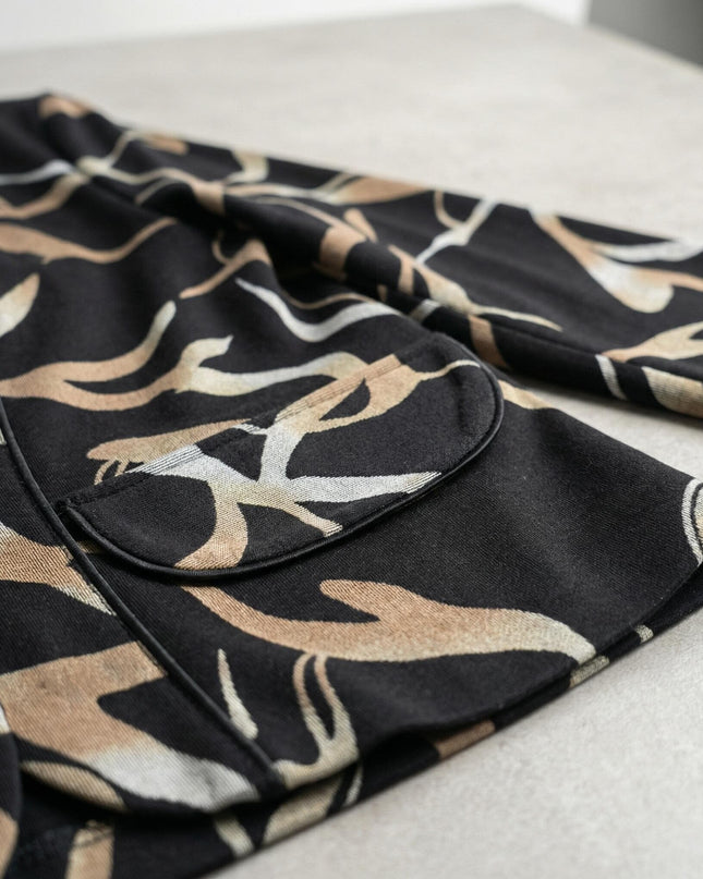 Λεπτομέρεια τσέπης και υφής από κομψό μαύρο σακάκι μεγάλα μεγέθη με αφηρημένο μπεζ σχέδιο σε κοντινή λήψη.