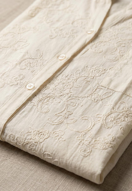 Κοντινή λεπτομέρεια σε μπεζ βαμβακερό πουκάμισο μεγάλα μεγέθη, διπλωμένο. Ξεχωρίζει η ανάλαφρη υφή, το ρομαντικό φλοράλ κέντημα και η σειρά με τα κουμπιά.