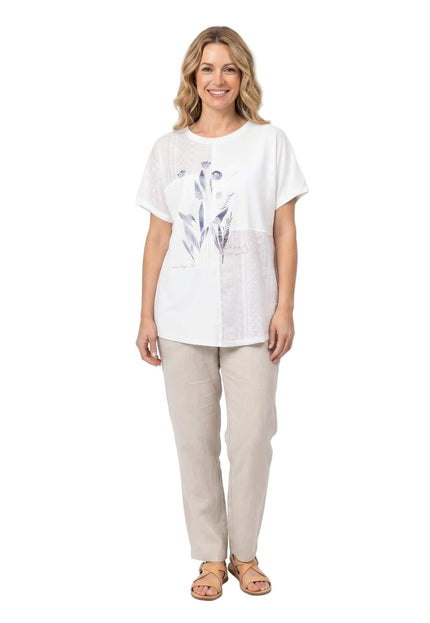 Λευκή καλοκαιρινή τουνίκ σε μεγάλα μεγέθη, φορεμένη από μοντέλο σε ολόσωμη λήψη με λευκό φόντο. Διαθέτει κομψό φλοράλ σχέδιο και κοντά μανίκια.