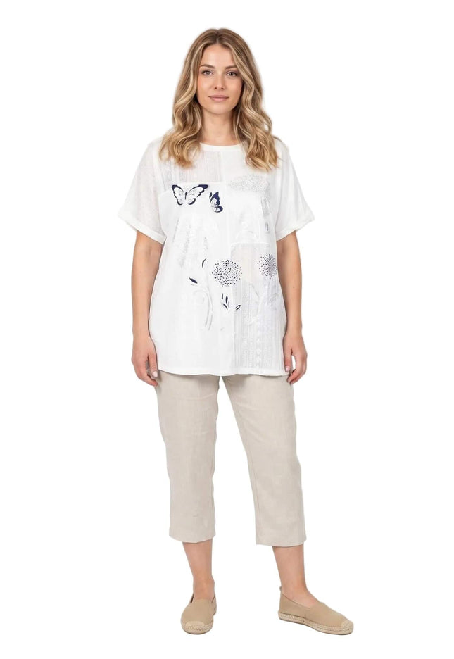 Λευκή βαμβακερή τουνίκ plus size με φλοράλ απλικέ. Ολόσωμη λήψη από μπροστά σε λευκό φόντο, με κοντά μανίκια και στρογγυλή λαιμόκοψη.