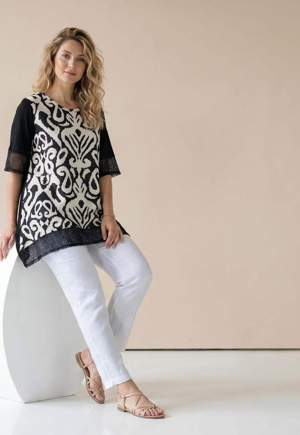 Ολόσωμη λήψη. Γυναικεία μαύρη καλοκαιρινή τουνίκ σε μεγάλα μεγέθη που εντυπωσιάζει με το ασπρόμαυρο μοτίβο και τα διχτυωτά στοιχεία στο τελείωμα.