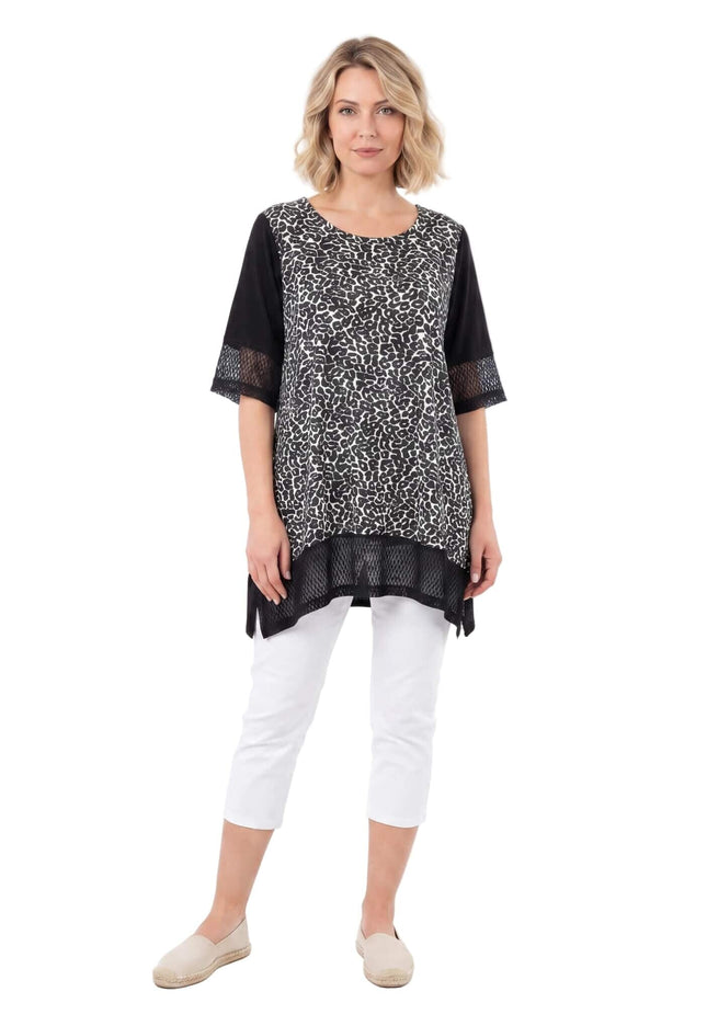 Ολόσωμη λήψη γυναίκας που φοράει την ασπρόμαυρη μάξι τουνίκ με δίχτυ σε μεγάλα μεγέθη, φωτογραφημένη σε λευκό φόντο.